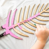 Pink and gold leaf-shaped object with a hand holding it on a white background