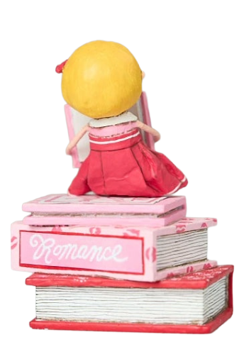 Hand-painted “Love Story” figurine by Lori Mitchell—sweet girl in pink and red dress perched atop a stack of romance books, lost in a love story